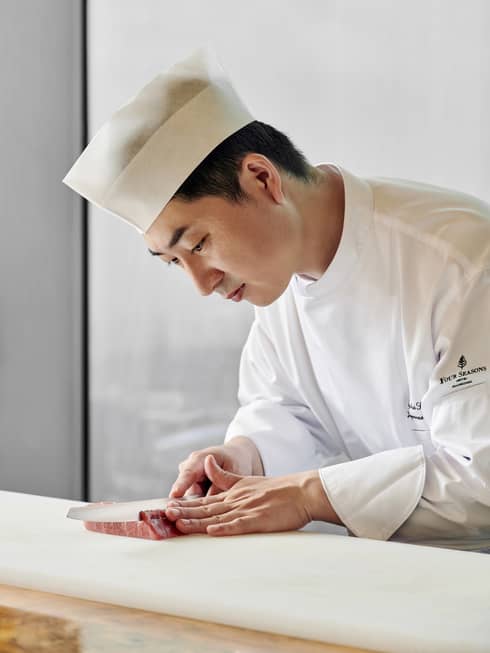 Chef de Cuisine Ryohei Sugawara slicing Wagyu beef