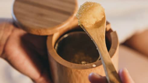 A spa staff member scoops some sugar scrub out of a bamboo container in Hawaii