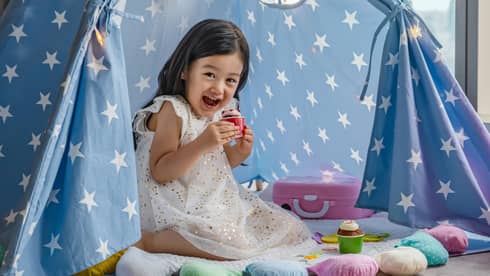 Smiling child playing with toys in a star-patterned tent