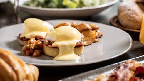 Sunday brunch table with Eggs Benedict, bacon and salad 