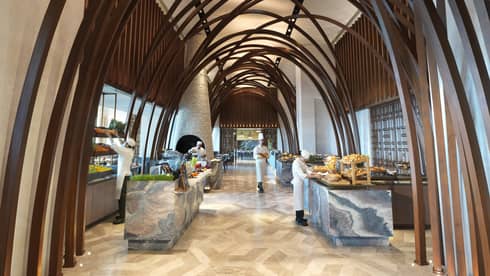 Soaring ceilings, wood arches over marble buffet tables where chefs prepare food