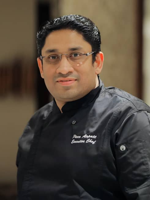 A chef in black clothes with glasses on.