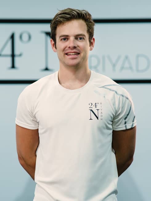 Max Whiteside standing with his arms behind his back wearing a white company shirt.