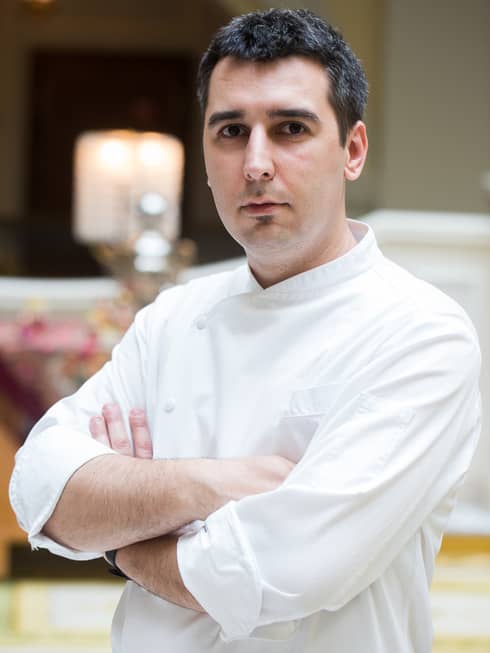Portrait photo of Executive Chef Matteo Guida with arms crossed, wearing white uniform