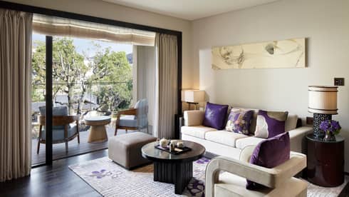 Living room sofa, armchair with plush purple pillows by open patio door, chairs