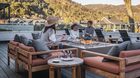 Three guests roasting marshmallows on an outdoor terrace.