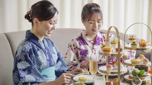 Two guests dressed in yukatas enjoy an afternoon tea spread