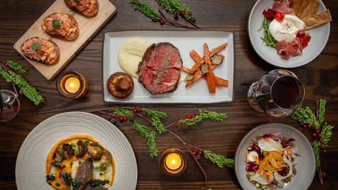 An assortment of holiday food on white and wood trays.
