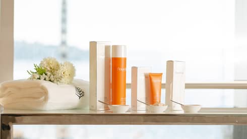 A selection of spa products in orange packaging near a window.
