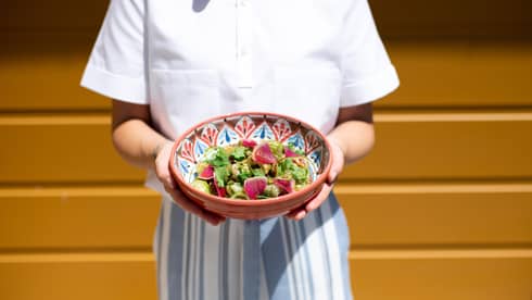 Person holding a Mexican-inspired serving dish with a fresh salad in it