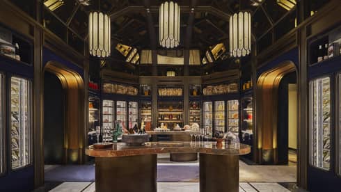 Cheese tasting room with a centre counter surrounded by glass cases of fine cheese and three large lanterns overhead