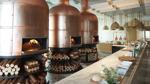 Three large fire burning pizza ovens behind a bar