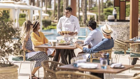 Chef greets table of four guests on outdoor terrace at Luna