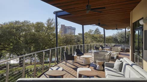 A balcony area of a bar restaurant looking out at trees and a city in the distance.