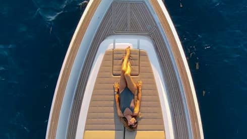 View from above of woman sunbathing on front deck of yacht.