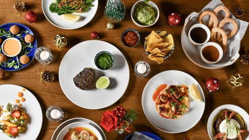 Overview of a wooden table filled with a variety of dishes along with festive ornaments and pinecone decorations