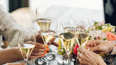 A group of guests toast glasses of champagne at a dining table