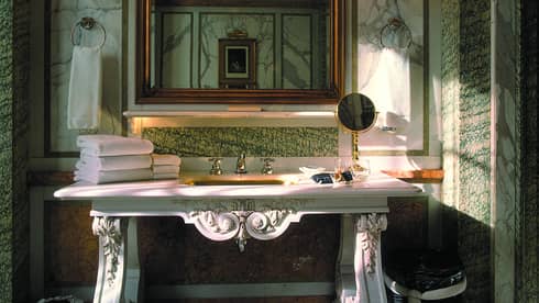 Elegant marble bathroom with decorative white vanity, folded white towels, mirror