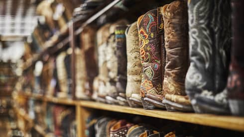 Shelves of cowboy boots of varying colours including black, brown and beige.