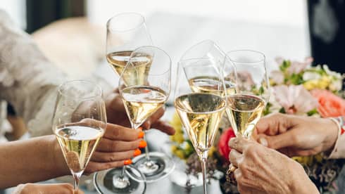 A group of guests toast glasses of champagne at a dining table