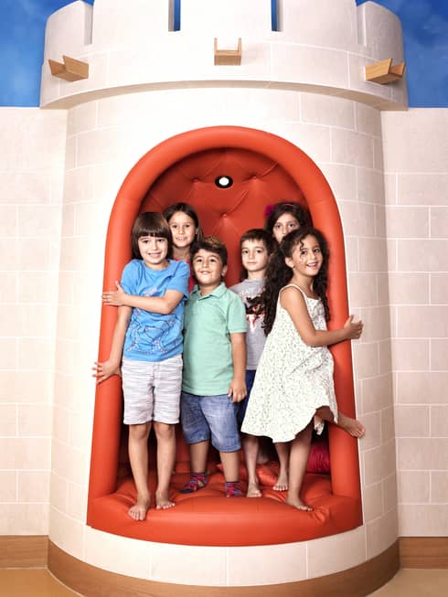 Six young children stand together inside a castle-style tower in the Hotel's Kid's Club