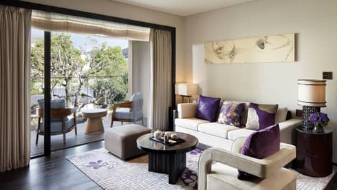 Living room sofa, armchair with plush purple pillows by open patio door, chairs