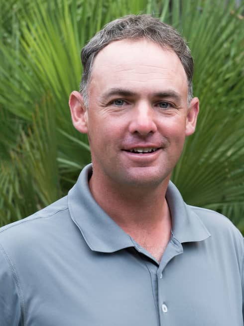 Portrait photo of Tennis Director David Wilson in front of palm leaves