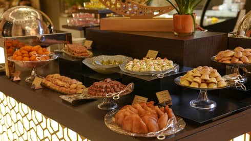 A buffet display of various Ramadan desserts served in either silver of glass platters