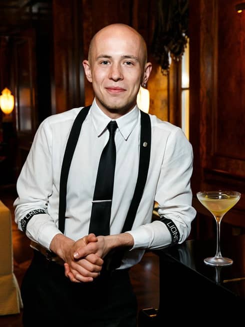 Assistant Bar Manager Taras Zavalnyuk resting elbow on bar beside cocktail