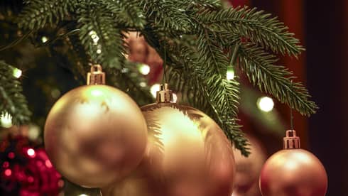 Gold ornaments hang on a christmas tree 