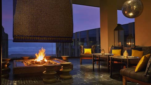 Patios sofas, beaches around large outdoor fireplace on Mint terrace at night
