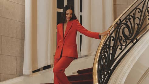 A woman in a red suit walking down stairs.