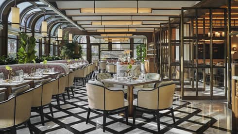Restaurant dining room with black-and-white tiled floors, wicker-backed dining chairs and a conservatory-style ceiling