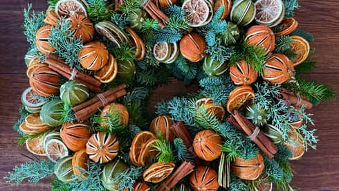 A wreath with greens and oranges.