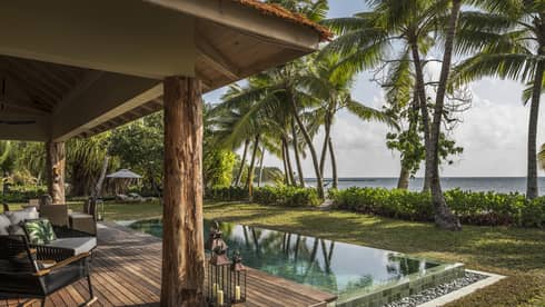 Two-Bedroom Villa wood patio with roof, infinity swimming pool, palm trees in front of ocean view