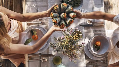 Guests sitting around a table and passing bowls of food.