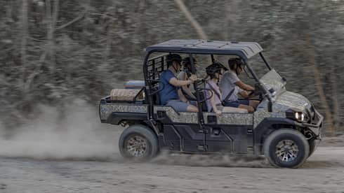 Four people speed along a dirt road in a 4x4 vehicle