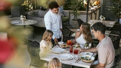 Family of four dines at a table on a restaurant terrace