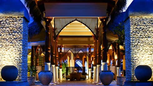 Outdoor entrance to restaurant, with illuminated steps, blue sky at desk, two planters
