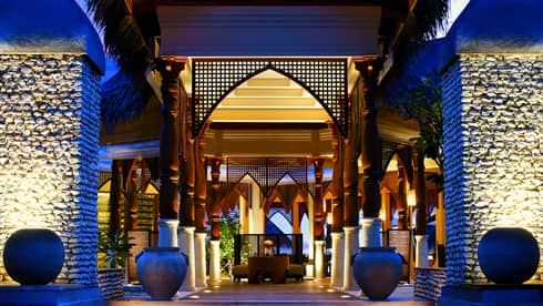 Outdoor entrance to restaurant, with illuminated steps, blue sky at desk, two planters