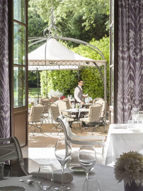 Il Palagio formal dining tables with flowers, candles, open doors to patio, server