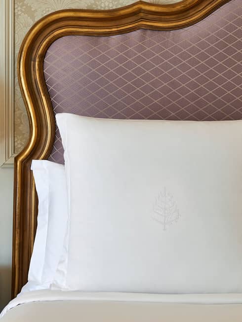 Close-up of white pillows against upholstered pink headboard with gold wood trim