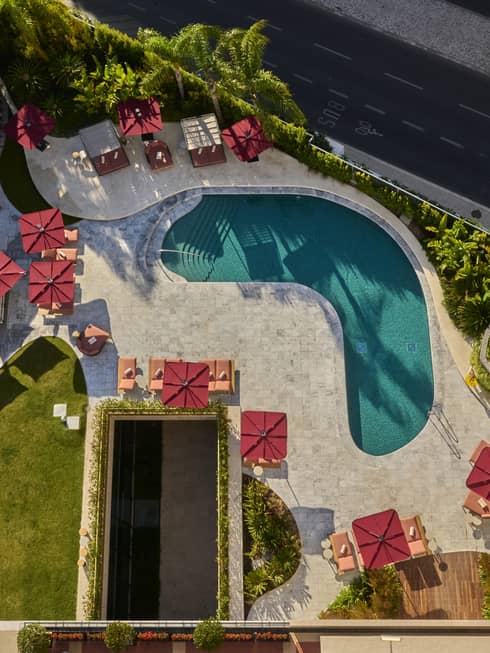 Aerial view of kidney-shaped pool surrounded by red umbrellas