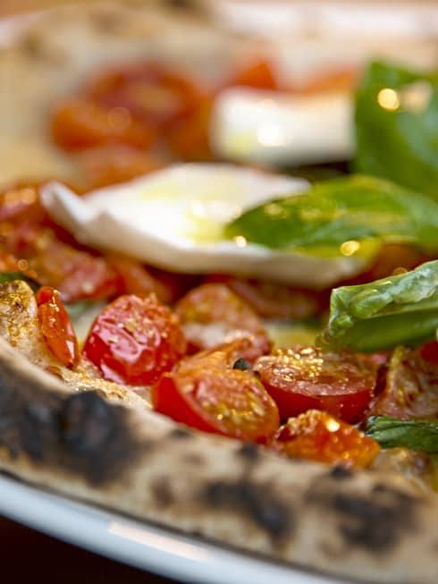 Close-up of Al Fresco signature pizza thin wheat crust, fresh cherry tomatoes, basil