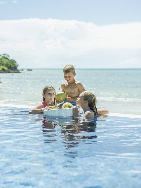 Two girls and a boy relax in the wading pool by the beach