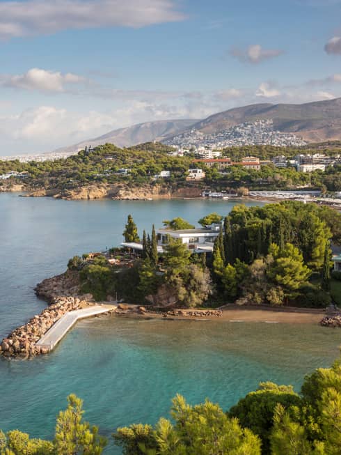 Aerial view of villa surrounded by trees on a peninsula, turquoise sea