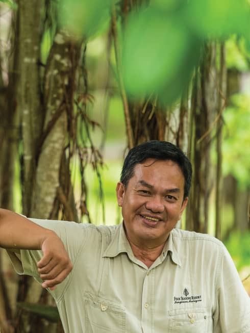 Portrait photo of Senior Naturalist Aidi Abdullah leaning against trees