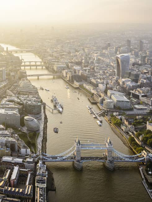 Aerial view of London city buildings along River Thames, London bridge in foreground 
