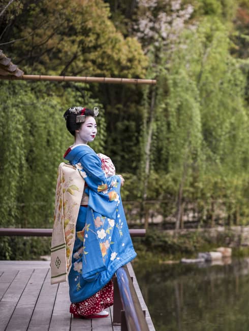 A geisha stands on the dock of the yoga barn and overlooks the serene lake