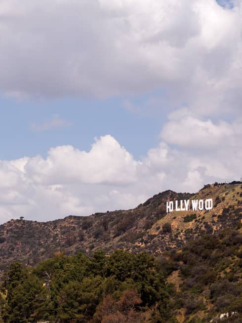 Hollywood sign on green Los Angeles hills against blue sky